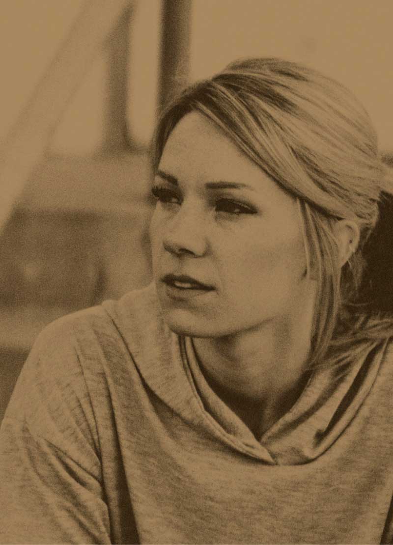 Woman in gray hoodie, contemplative expression.